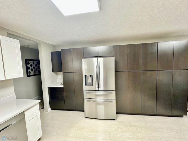 kitchen featuring a textured ceiling, light hardwood / wood-style flooring, white cabinets, and appliances with stainless steel finishes