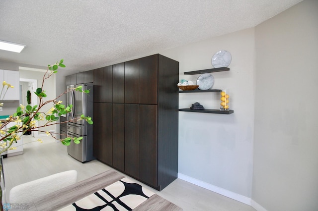 interior space featuring white cabinetry, dark brown cabinetry, stainless steel fridge, and a textured ceiling