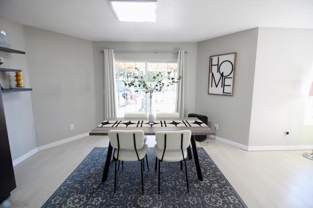 dining space with light hardwood / wood-style floors and a textured ceiling