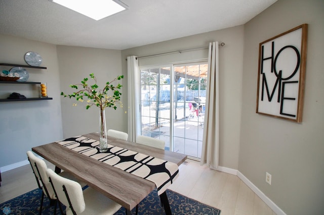 dining room featuring a skylight and light hardwood / wood-style flooring