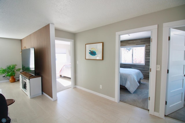 hall featuring light hardwood / wood-style flooring and a textured ceiling