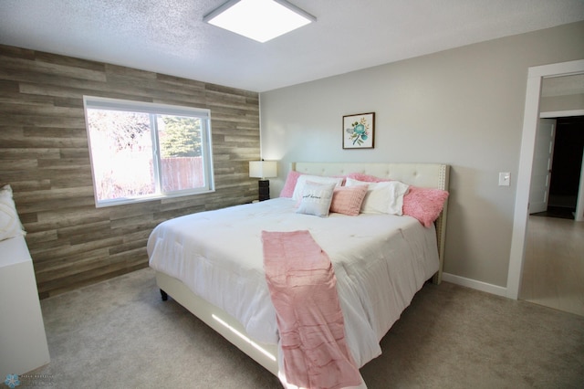 bedroom featuring carpet floors, wooden walls, and a textured ceiling