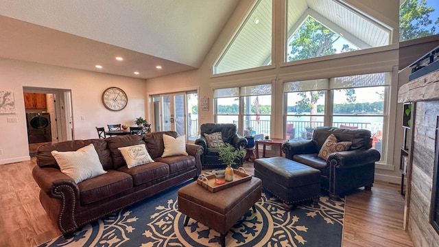 living room featuring washer / clothes dryer, a healthy amount of sunlight, a water view, and hardwood / wood-style flooring