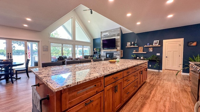 kitchen featuring light stone counters, a large fireplace, a kitchen island, and light hardwood / wood-style flooring