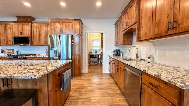 kitchen featuring sink, light hardwood / wood-style flooring, stainless steel appliances, and light stone countertops