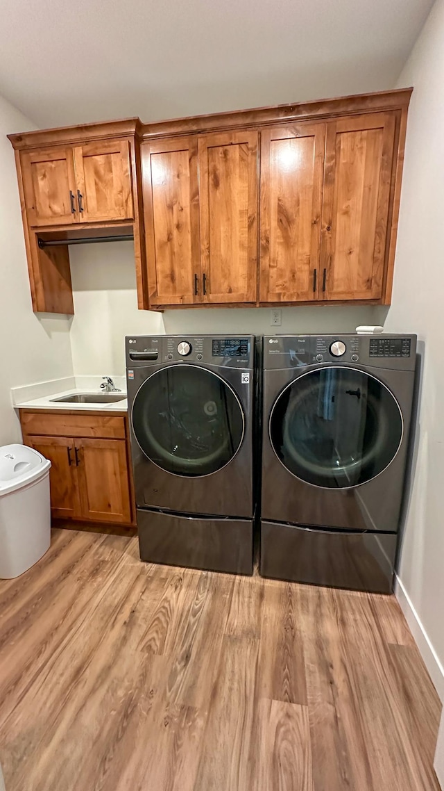 washroom with cabinets, washer and dryer, sink, and light hardwood / wood-style floors