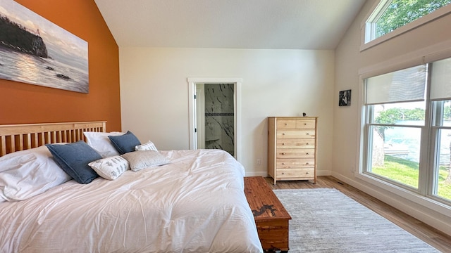 bedroom with vaulted ceiling, light hardwood / wood-style floors, and ensuite bath