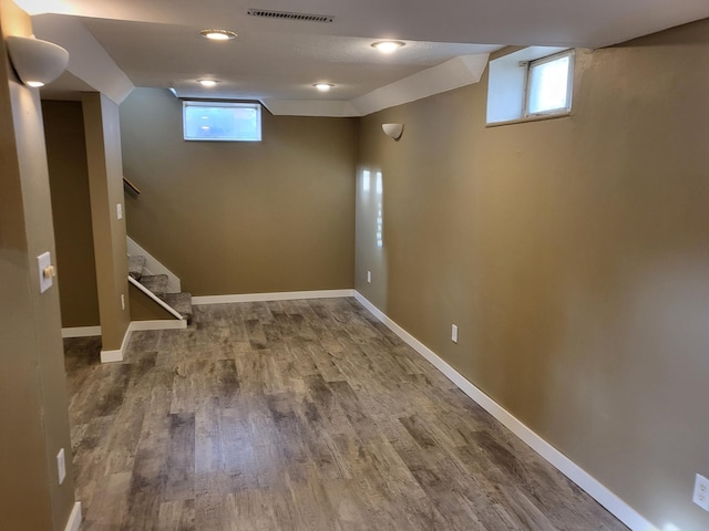 below grade area featuring a wealth of natural light, visible vents, baseboards, and wood finished floors