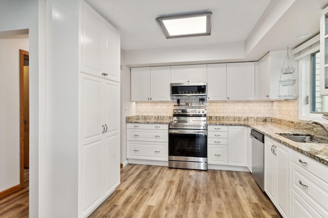 kitchen with white cabinetry, sink, light stone counters, and stainless steel appliances