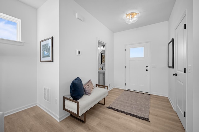 foyer featuring light wood-style floors, baseboards, and visible vents