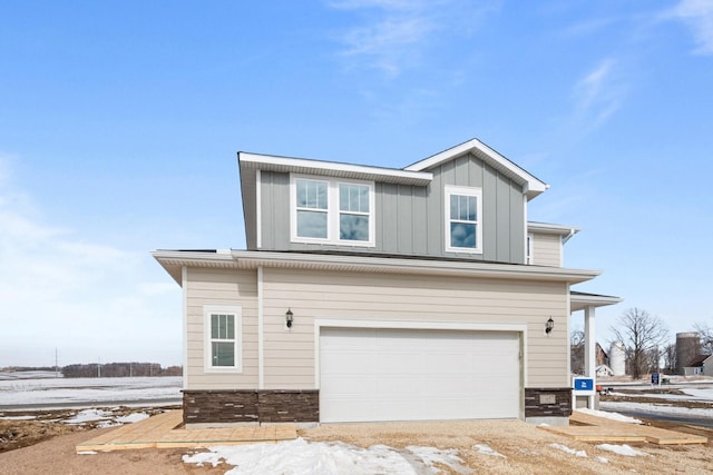 view of front of home featuring a garage, stone siding, and board and batten siding