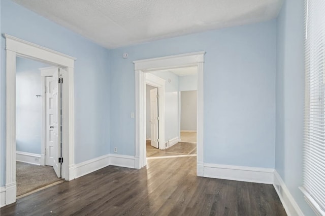 spare room with dark hardwood / wood-style floors and a textured ceiling