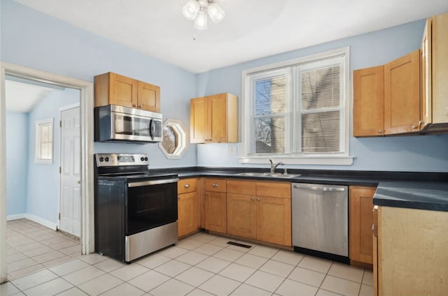 kitchen with stainless steel appliances, light tile patterned flooring, sink, and ceiling fan