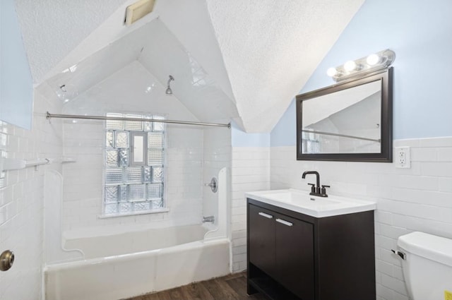 full bathroom featuring hardwood / wood-style floors, lofted ceiling, tile walls, toilet, and a textured ceiling