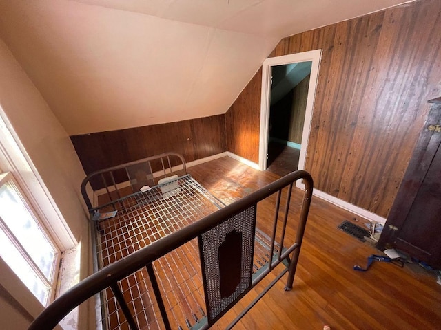 stairway featuring lofted ceiling, hardwood / wood-style floors, and wood walls