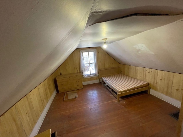 unfurnished bedroom with dark wood-type flooring, lofted ceiling, and wood walls