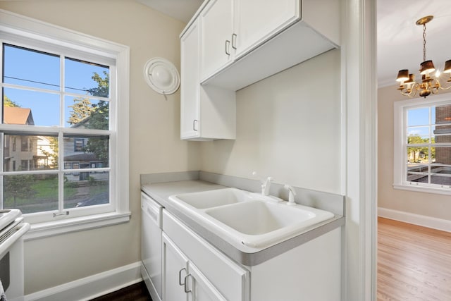 kitchen with sink, white appliances, hardwood / wood-style flooring, white cabinets, and a chandelier