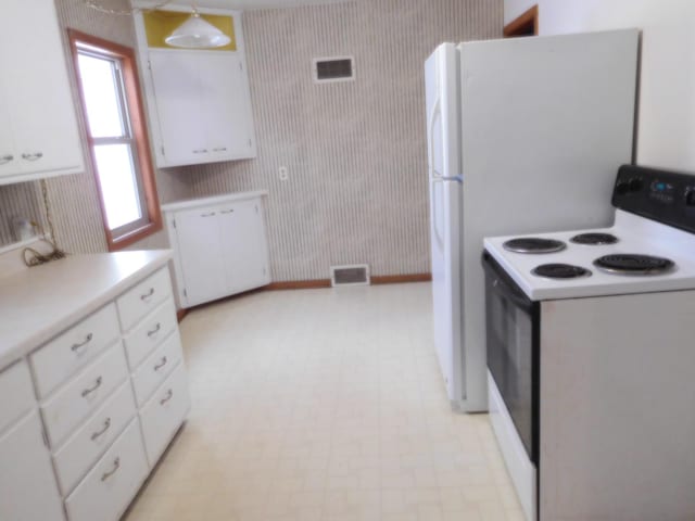 kitchen featuring pendant lighting, white electric range oven, and white cabinets