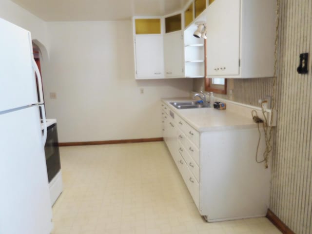 kitchen featuring sink, range, white cabinets, and white refrigerator