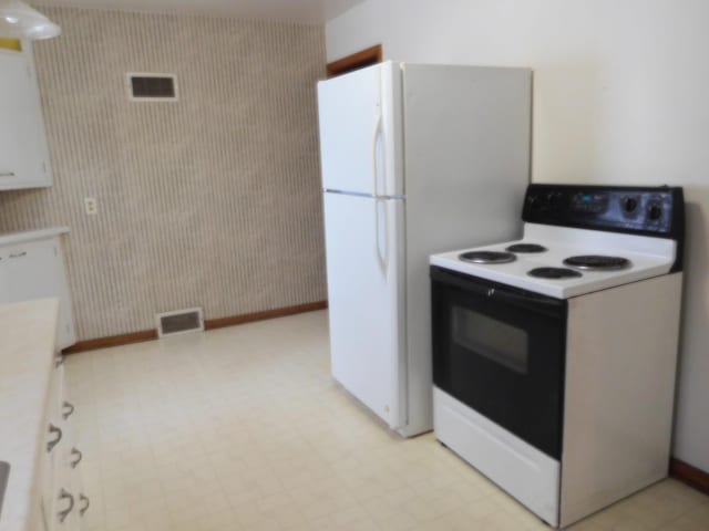 kitchen featuring electric range oven and white cabinets