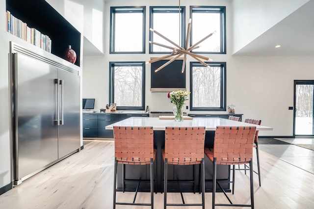 kitchen with a breakfast bar, a healthy amount of sunlight, and stainless steel built in fridge