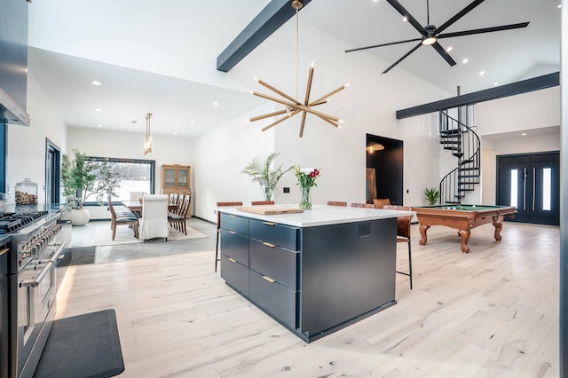 kitchen featuring double oven range, high vaulted ceiling, a center island, light hardwood / wood-style floors, and decorative light fixtures