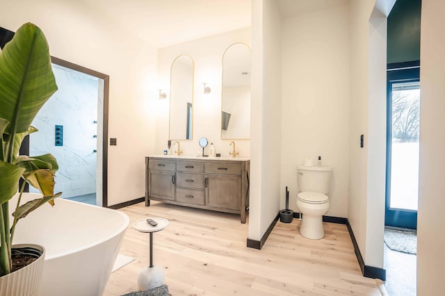 bathroom featuring wood-type flooring, toilet, vanity, and a washtub