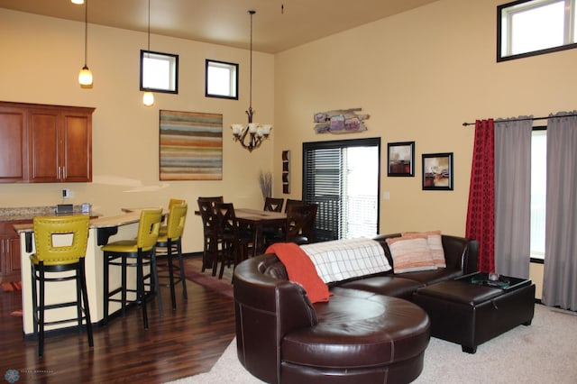 living room with dark hardwood / wood-style flooring, a notable chandelier, plenty of natural light, and a high ceiling