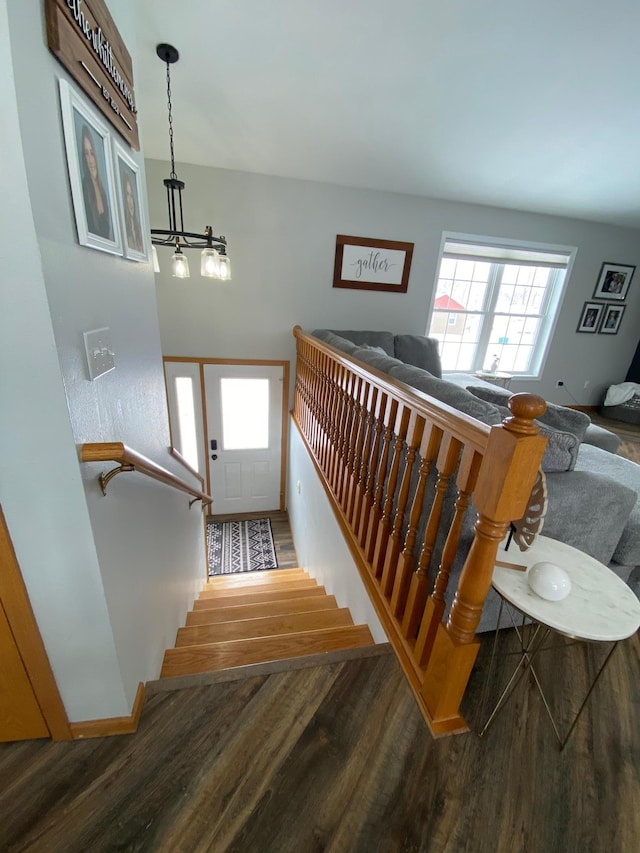 staircase with hardwood / wood-style flooring and a notable chandelier