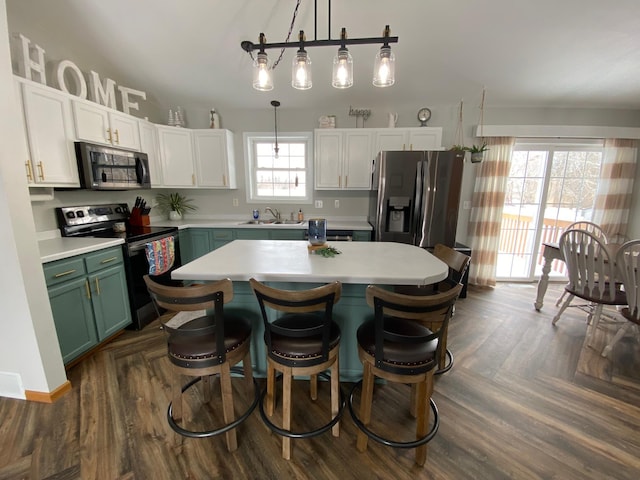 kitchen with a kitchen island, appliances with stainless steel finishes, decorative light fixtures, white cabinetry, and sink