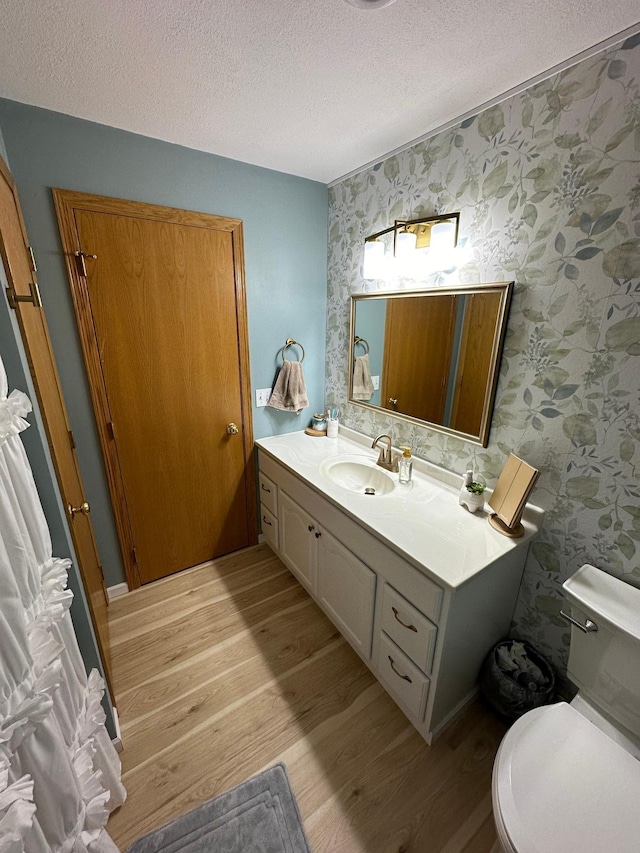 bathroom featuring wood-type flooring, toilet, a textured ceiling, and vanity