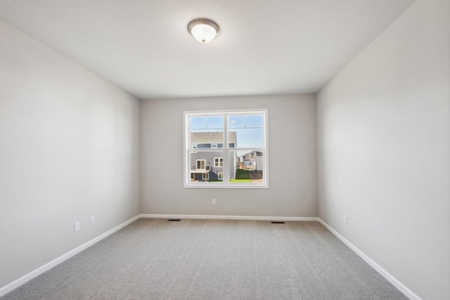 carpeted empty room featuring a textured ceiling