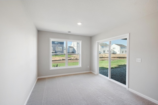 empty room with light carpet and a textured ceiling