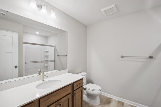 bathroom with vanity, a textured ceiling, a shower with door, and toilet