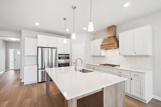 kitchen featuring sink, custom range hood, white cabinets, and appliances with stainless steel finishes