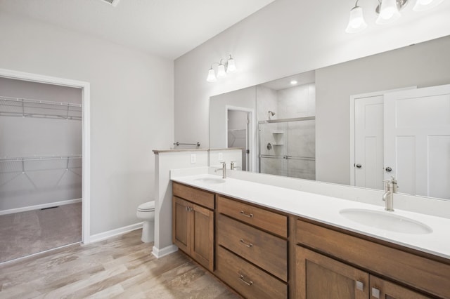 bathroom with a shower with door, vanity, hardwood / wood-style flooring, and toilet