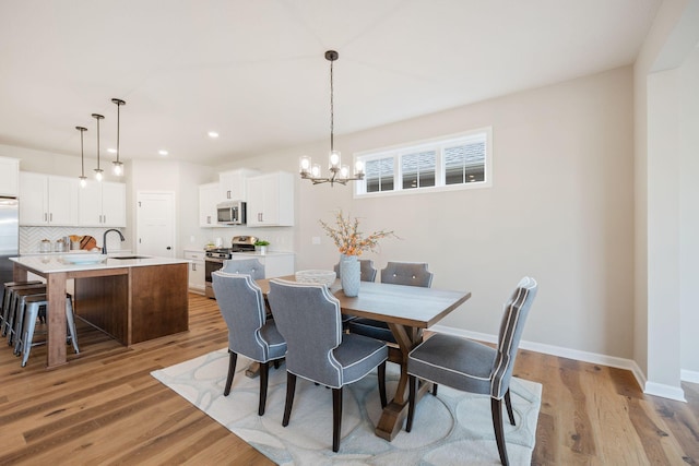 dining area featuring a chandelier, light hardwood / wood-style floors, and sink