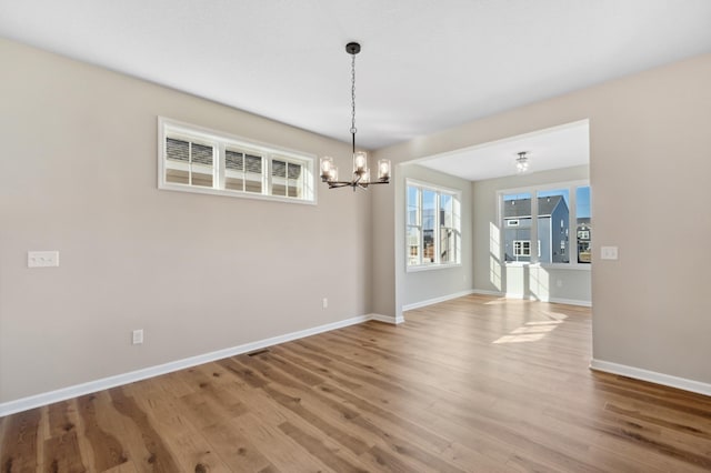 unfurnished dining area featuring a notable chandelier and hardwood / wood-style flooring