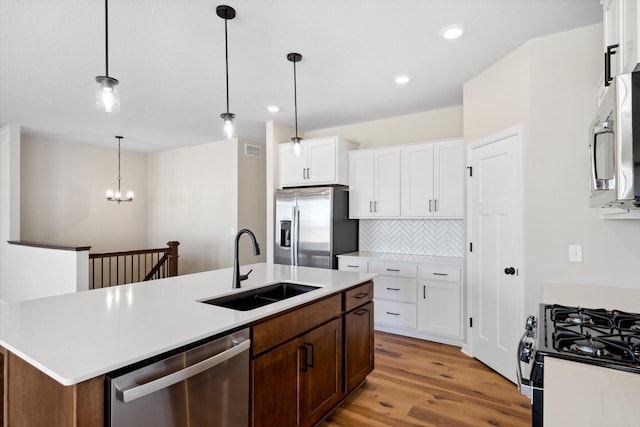 kitchen featuring sink, white cabinetry, decorative light fixtures, a center island with sink, and stainless steel appliances