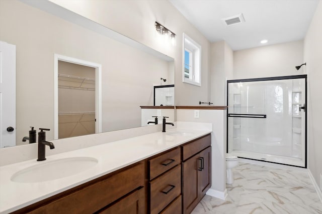 bathroom featuring vanity, a shower with door, and toilet