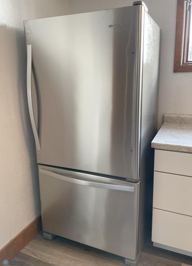 room details with stainless steel fridge and light hardwood / wood-style floors