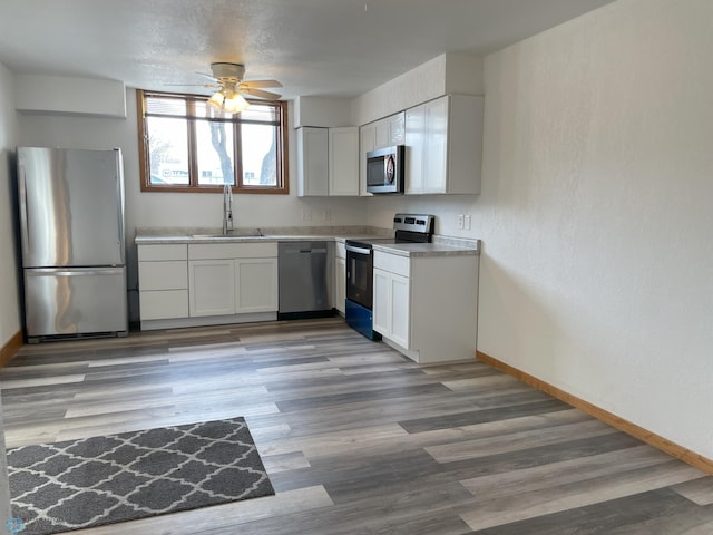 kitchen with stainless steel appliances, white cabinetry, sink, and dark hardwood / wood-style flooring