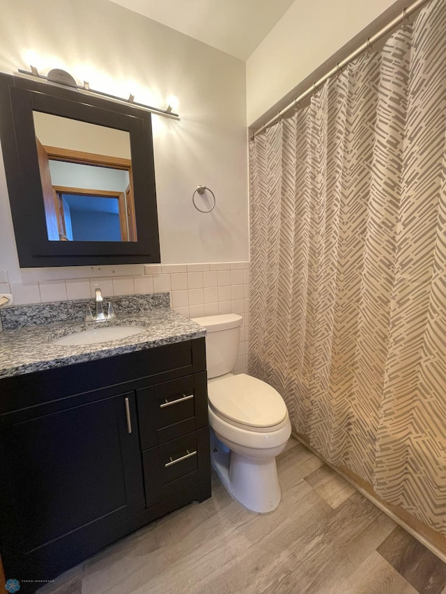 bathroom featuring tile walls, vanity, wood-type flooring, and toilet