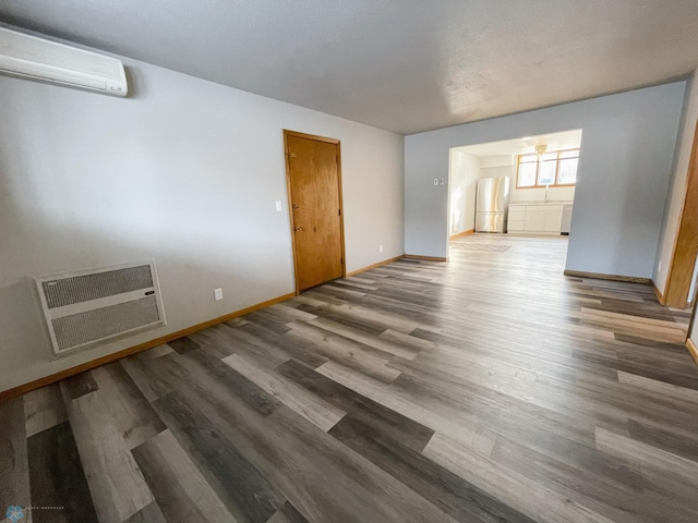 unfurnished room featuring a wall mounted AC, hardwood / wood-style floors, and heating unit