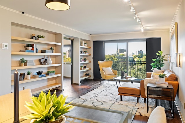 living area featuring dark wood-type flooring, crown molding, built in shelves, and rail lighting