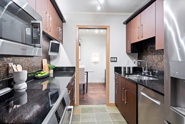 kitchen featuring sink, backsplash, dark stone counters, stainless steel appliances, and crown molding