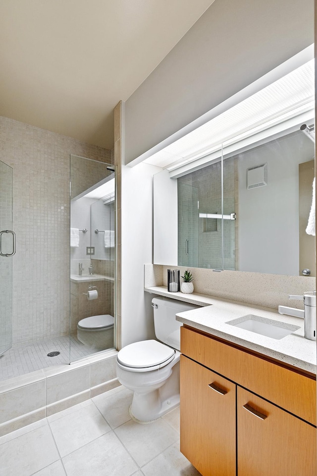 bathroom featuring tile patterned flooring, vanity, walk in shower, and toilet