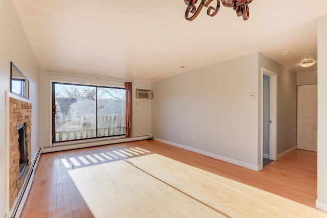 unfurnished living room with a wall mounted air conditioner, wood-type flooring, and a baseboard heating unit