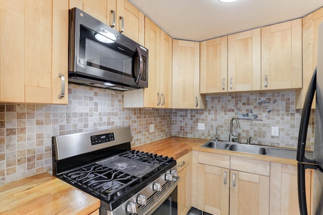 kitchen with stainless steel gas range oven, sink, light brown cabinets, and wooden counters