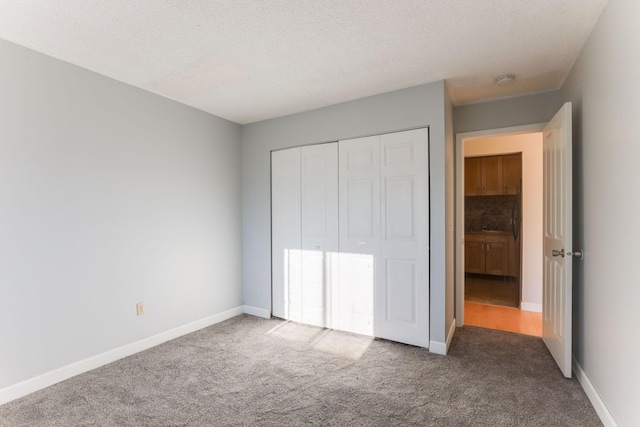 unfurnished bedroom featuring a textured ceiling, dark carpet, and a closet